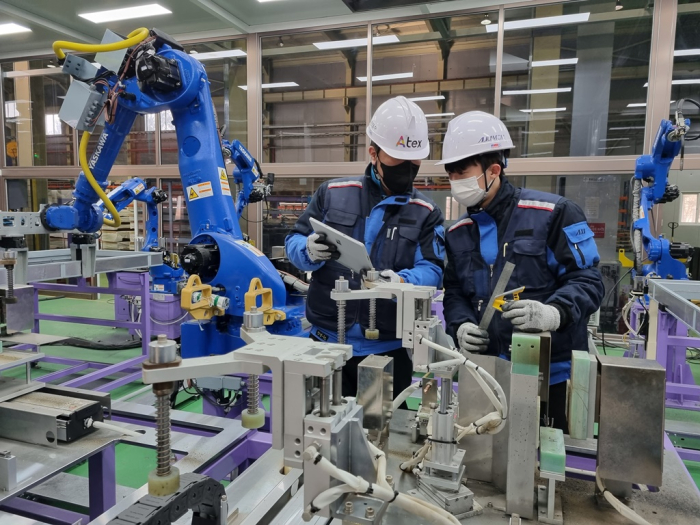 Aju Steel workers check a robot at a factory's automated production line