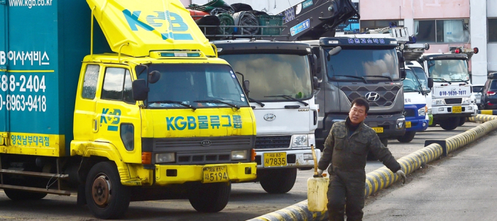 A driver is carrying a DEF or diesel exhaust fluid product, essential for diesel vehicles