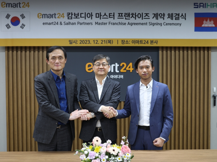 E-Mart24　CEO　Han　Chae-yang　(center),　Saihan　Partners　Director　David　Sambo　(right)　and　Hanlim　Architecture　Group　Chairman　Park　Jin-sun　shake　hands　after　signing　a　master　franchise　agreement　on　Dec.　23,　2023　in　Seoul