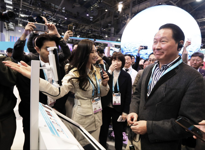 SK Group Chairman Chey Tae-won (right) tests an AI fortuneteller service at SK Telecom's booth during CES 2024 in Las Vegas
