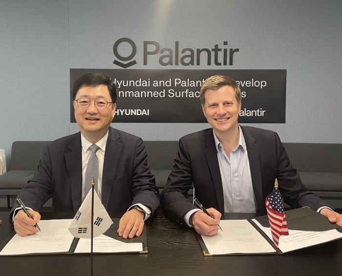 Joo　Won　Ho　(left),　chief　executive　of　HD　Hyundai　Heavy　Industries’　naval　and　special　ship　business　unit,　and　Ryan　Taylor,　Palantir’s　chief　revenue　officer　and　chief　legal　officer,　sign　a　cooperation　deal　to　develop　an　unmanned　surface　vehicle　at　Palantir’s　office　in　Washington,　D.C.　(Courtesy　of　HD　Hyundai)