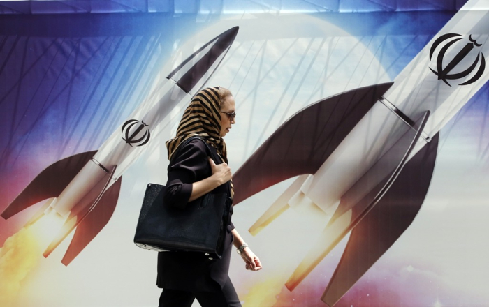 An Iranian woman walks past an anti-Israel banner with pictures of Iranian missiles in Tehran, Iran, on April 16, 2024 (Courtesy of EPA via Yonhap)