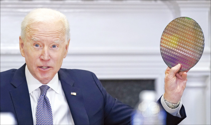 Joe Biden holds up a silicon wafer during a virtual meeting with CEOs to discuss supply chain issues at the White House in April 2021 (Courtesy of AP, Yonhap News)