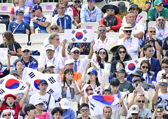 Hyundai　Motor　Chairman　Chun　Euisun　(center　with　black　sunglasses)　holds　up　a　Korean　national　flag　to　support　the　Korean　archers　who　won　the　women's　team　gold　medal　at　the　Summer　Olympics　2024　in　Paris