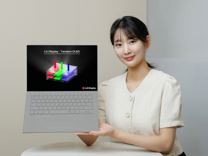 An LG Display employee displays a laptop fitted with a tandem OLED screen