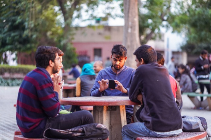 A　group　of　university　students　sit　at　an　outdoor　table　at　the　Jamia　Millia　Islamia　campus　in　New　Delhi,　India　(Courtesy　of　Getty　Images) 