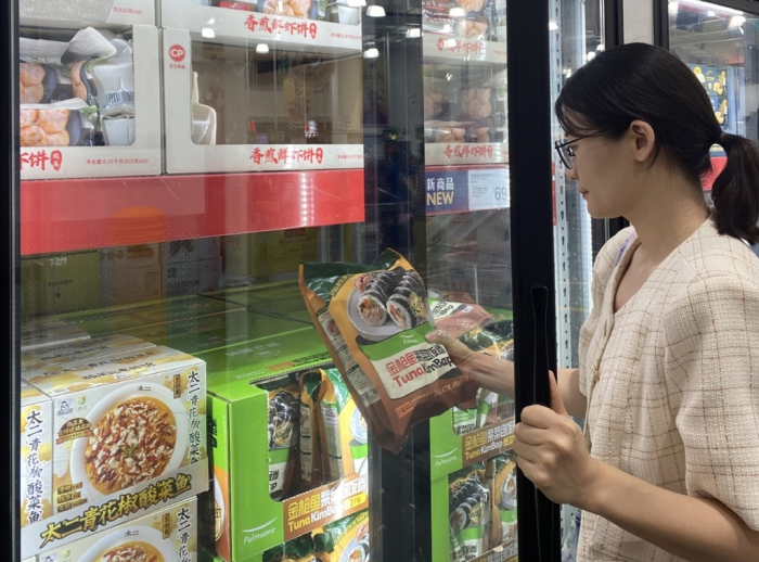 A　customer　picks　up　a　bag　of　Pulmuone　tuna　gimbap　at　a　store　in　China　(Courtesy　of　Pulmuone)