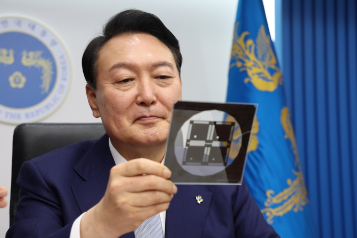 President　Yoon　Suk　Yeol　looks　at　a　photomask　used　to　produce　a　pattern　on　a　substrate　or　a　wafer,　during　a　cabinet　meeting