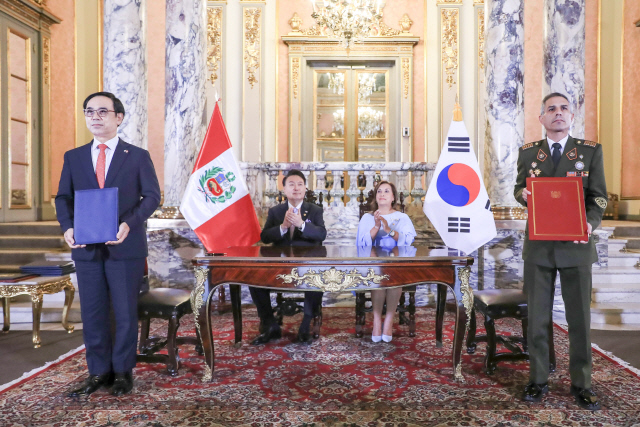 Hyundai　Rotem　President　Lee　Yong-bae　(left)　and　Jorge　Zapata　(right),　CEO　of　Peru’s　Army　Weapons　and　Ammunition　Factory,　pose　at　a　partnership　signing　ceremony　in　Lima,　Peru　on　Saturday,　with　President　Yoon　Suk　Yeol　(second　from　left)　and　his　Peruvian　counterpart　Dina　Boluarte　in　attendance　(Courtesy　of　Presidential　office)