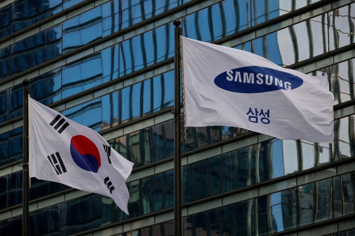 A　flag　bearing　the　Samsung　logo　flutters　next　to　the　Korean　flag　in　front　of　an　office　building　in　Seoul