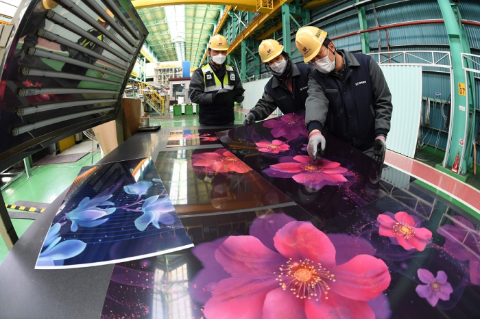 Dongkuk CM employees inspect color-coated steel sheets at the company's steel mill in Busan, South Korea