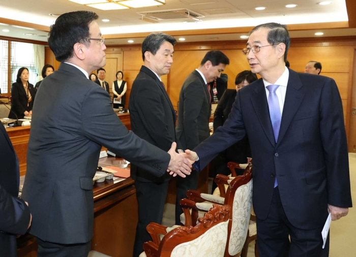 Acting President Han (right) shakes hands with Finance Minister Choi Sang-mok at the Government Complex Seoul on March 24, 2025 (Press pool photo)