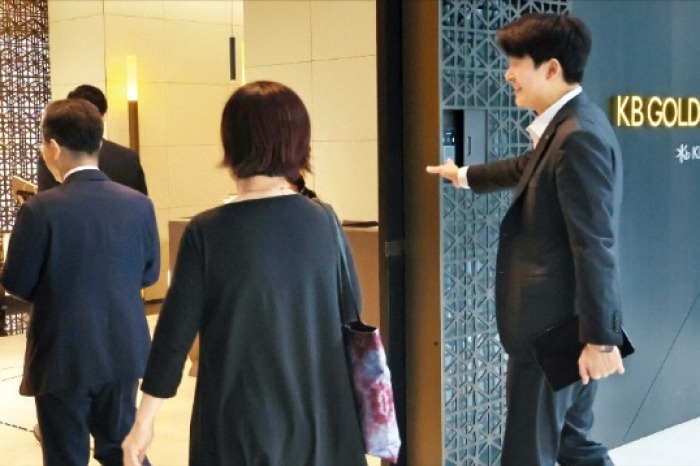 A Kookmin Bank private banker guides clients into a wealth management office