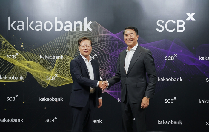 Yun Ho-Young, CEO of KakaoBank (left), and SCBX CEO Arthid Nanthawithaya shakes hands after agreeing to launch an internet bank in Thailand in June 2023