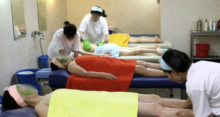 Clients receive body scrubbing services in a public bathhouse